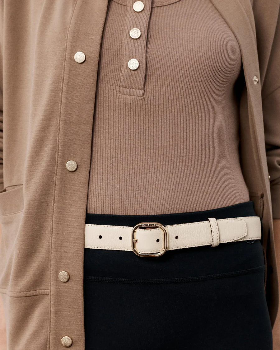 Elegant reversible leather belt in cream, showcased with gold buttoned cardigan.