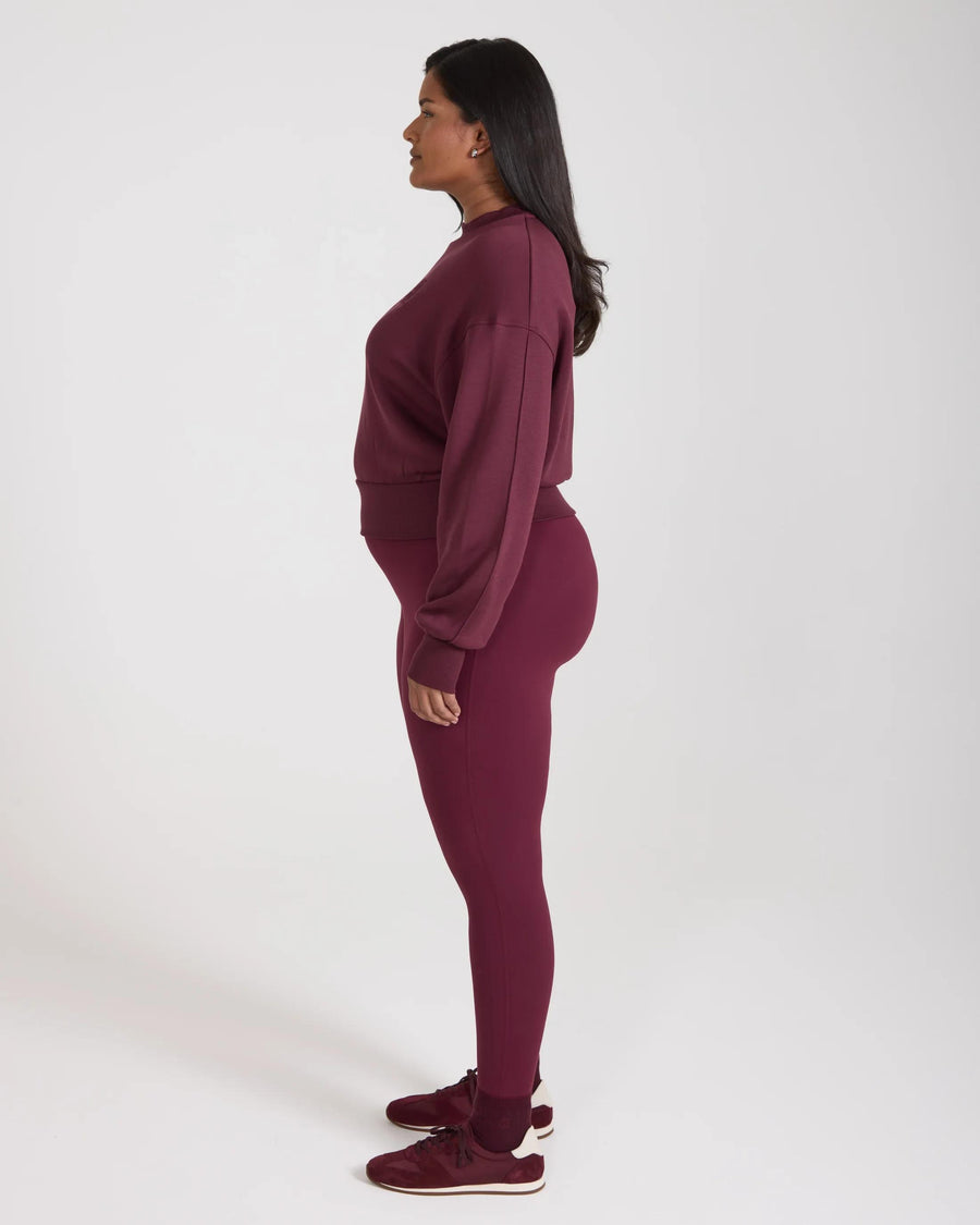 Model wearing Emello purple leggings with belt loops, side view.