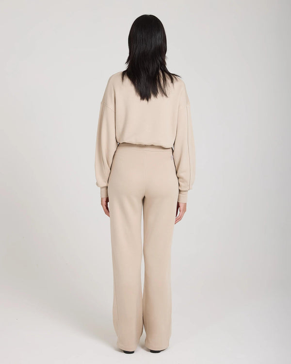 Back view of model wearing beige wide-leg lyocell fleece pants by Emello, showcasing relaxed fit and subtle elegance.