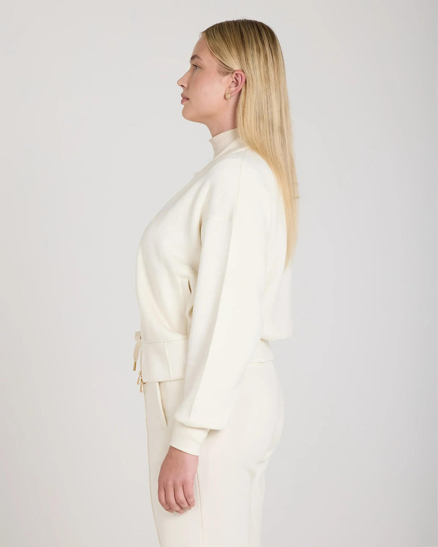 Side profile of a model wearing a cream zip-through jacket in buttery-soft lyocell, showcasing gold hardware and relaxed fit.