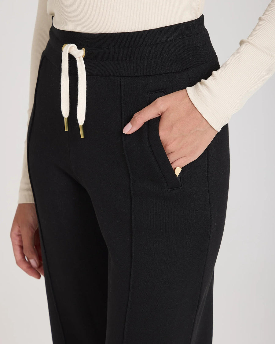 Black lyocell trousers with concealed zip pockets and embroidered badge, featuring a gold-finish drawcord waistband.