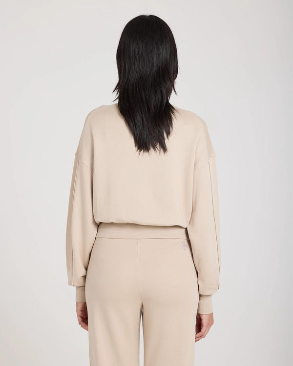 Back view of a beige lyocell fleece sweatshirt with a relaxed fit and debossed logo badge.