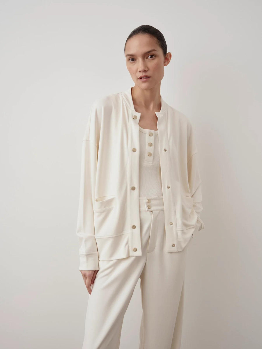 Emello Modal Popper Jacket in cream, featuring a collarless silhouette with popper fastenings. Relaxed shoulders and a smooth draped finish over matching cream trousers.