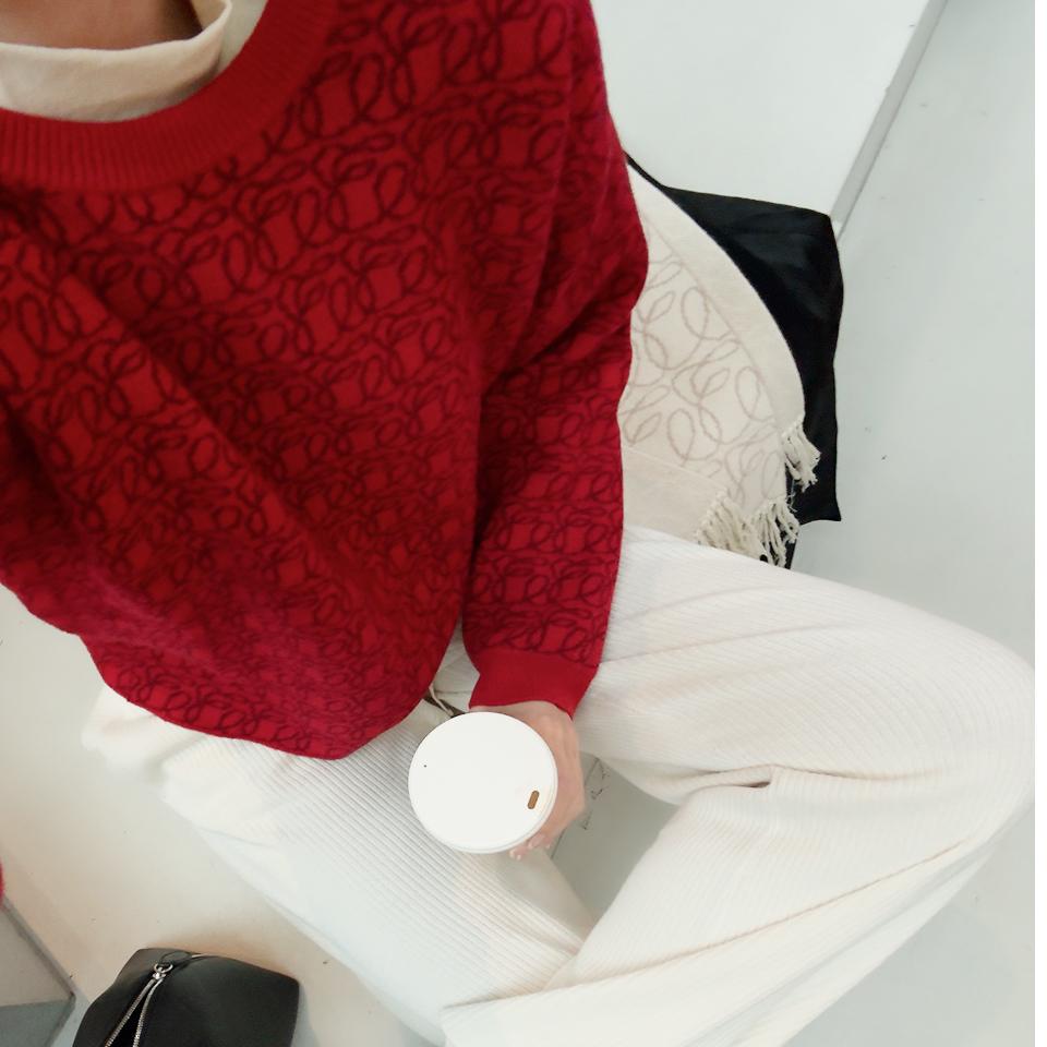 Red jacquard knit with tonal monogram detailing, styled with soft ivory ribbed trousers