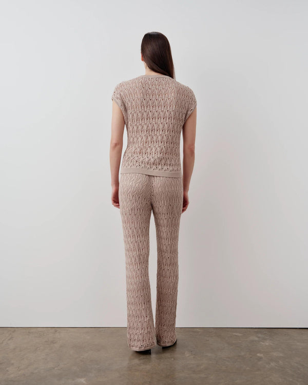 Back view of model wearing Emello open knit short sleeve top in neutral beige
