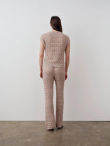 Back view of model wearing Emello open knit short sleeve top in neutral beige