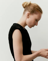 Side profile of a model wearing Emello's Panelled Open Knit Midi Dress in black, showcasing the detailed texture and design.