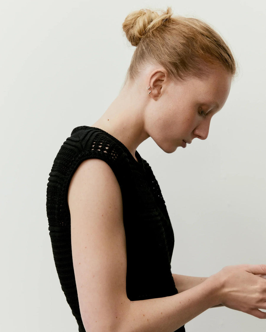 Side profile of a model wearing Emello's Panelled Open Knit Midi Dress in black, showcasing the detailed texture and design.