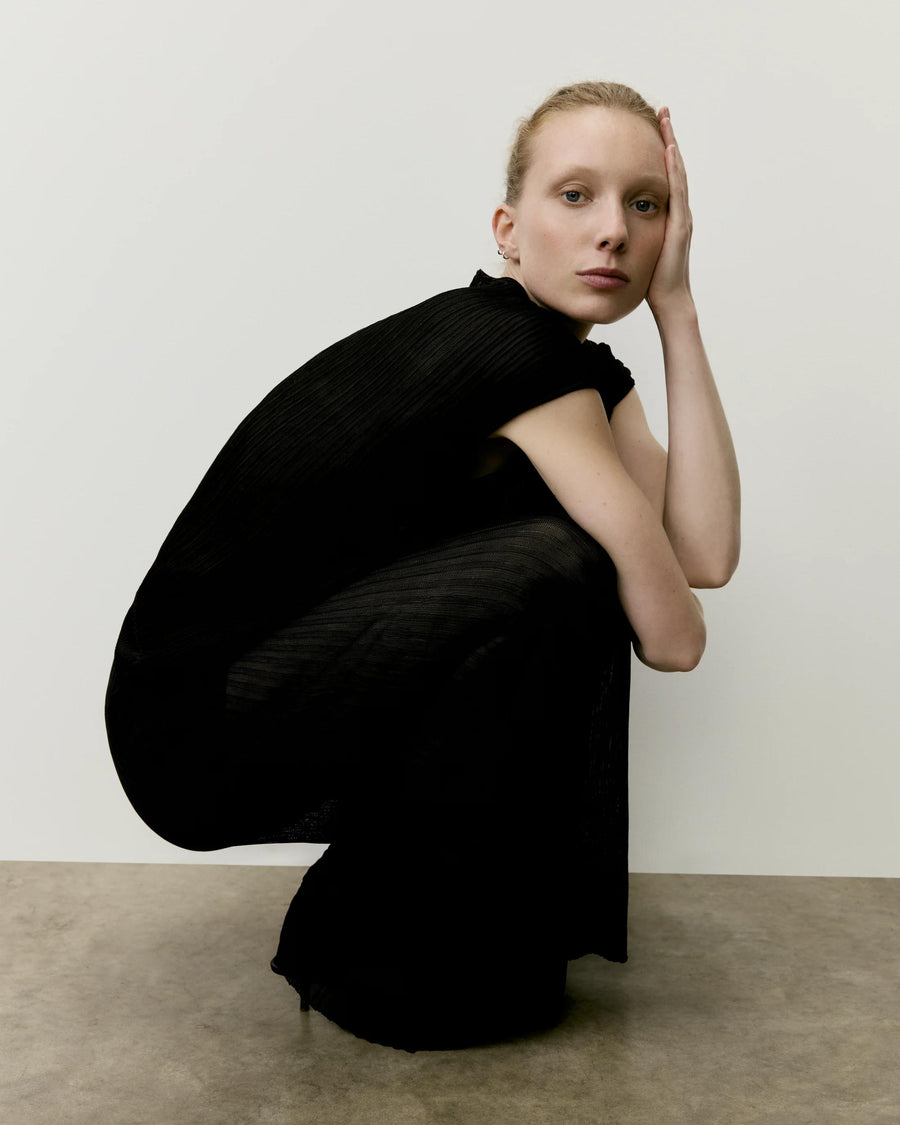 Model wearing Emello's black Plissé Knit Trousers, exuding refined elegance and fluid movement.