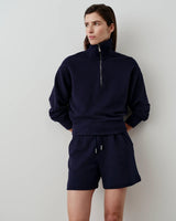 Woman wearing Emello embroidered pocket shorts and matching sweatshirt in navy.