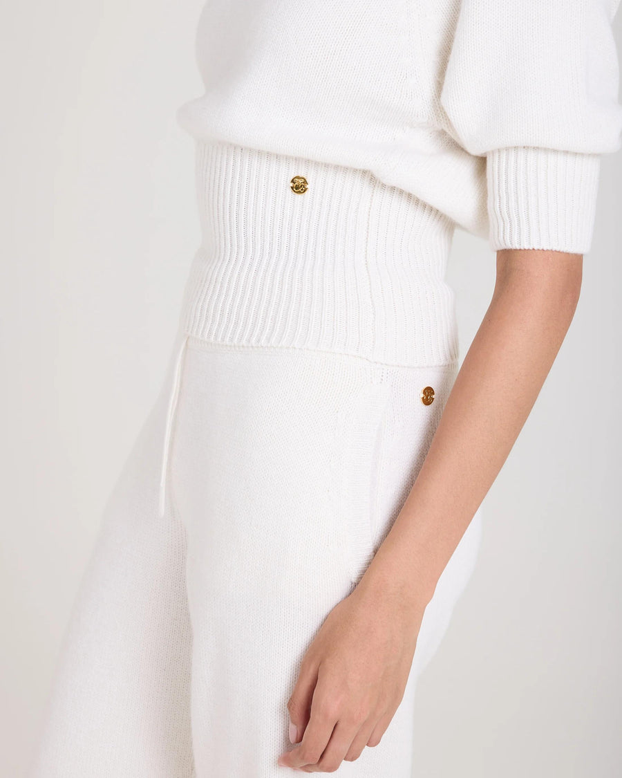 Side view of cream puff sleeve sweater in merino wool and cashmere blend with gold hardware detailing.