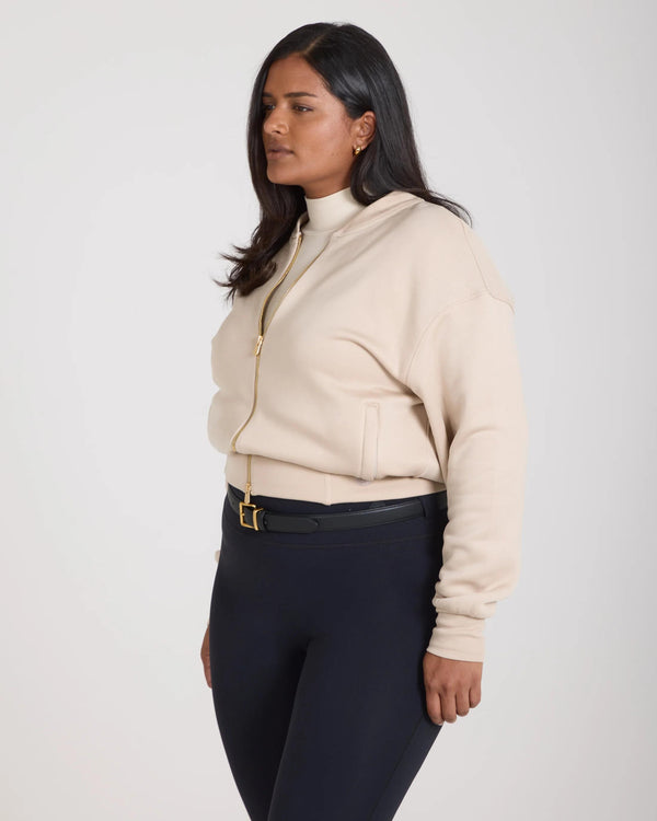 Emello beige lyocell fleece zip-through jacket on model, showcasing relaxed fit with gold-finish zip and embroidered details.