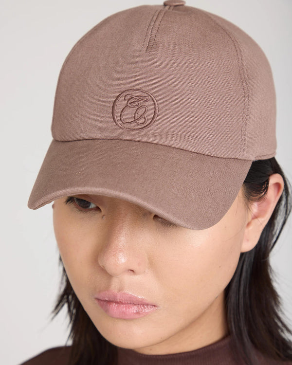 Luxury taupe cap featuring Emello's signature embroidery, crafted from brushed cotton elastane twill, worn by a model.