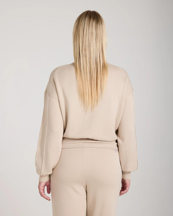 Back view of a relaxed beige Emello Lyocell Fleece Sweatshirt with long sleeves and ribbed hem.