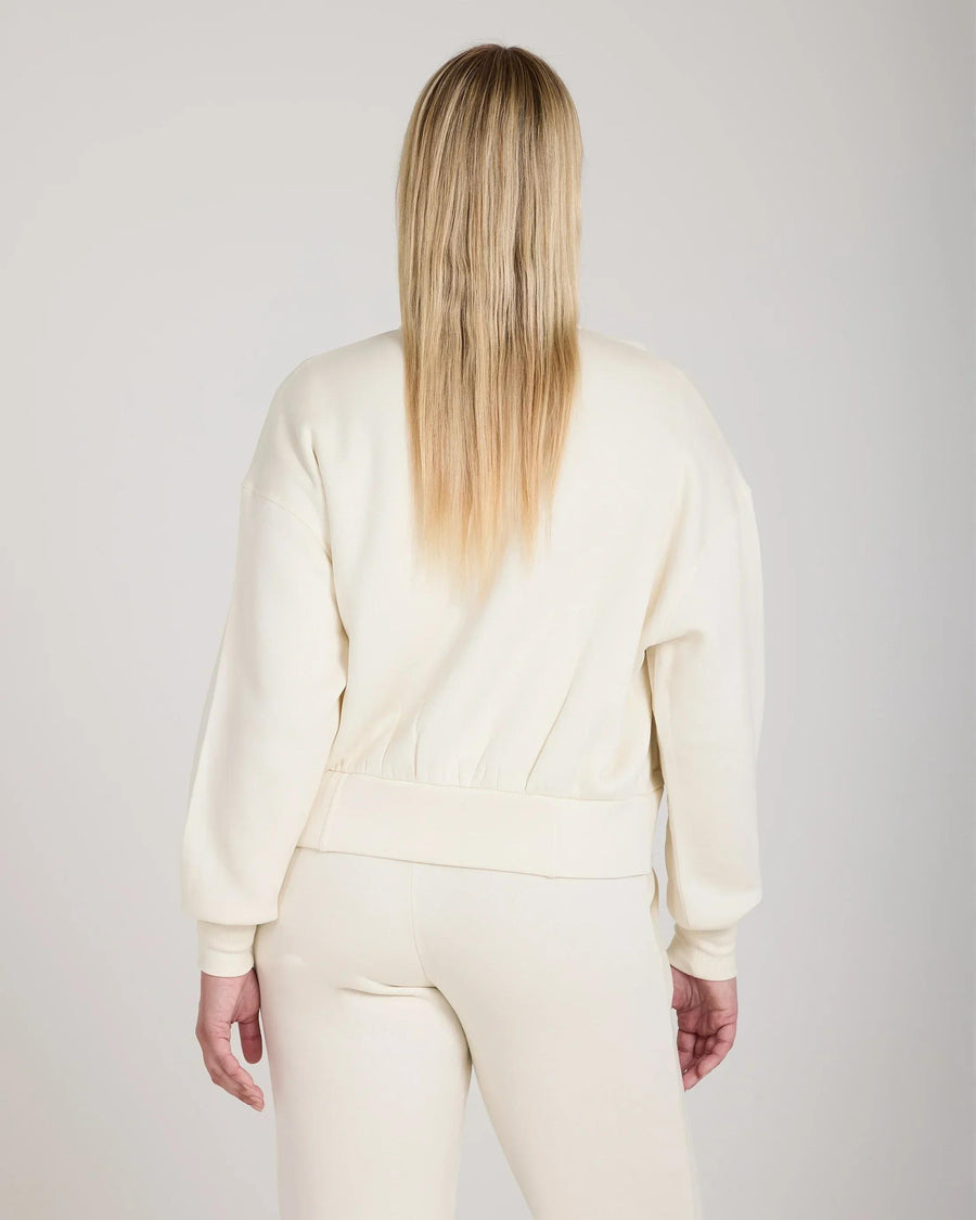 Back view of model wearing cream zip-through jacket in soft lyocell with relaxed fit and gold hardware.