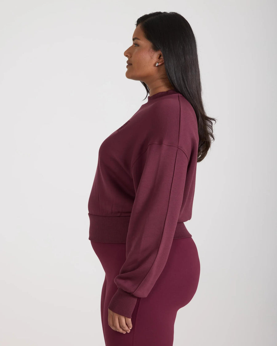 Side profile of a model wearing a Emello Fig sweatshirt with embossed details, crafted in buttery-soft lyocell fleece.
