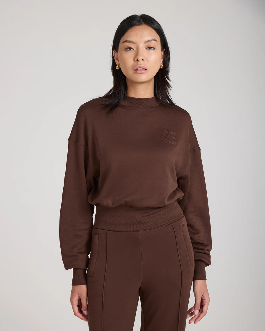 Model wearing the Mello Lyocell Fleece Sweatshirt in chocolate, showcasing a relaxed silhouette with embossed logo detail.