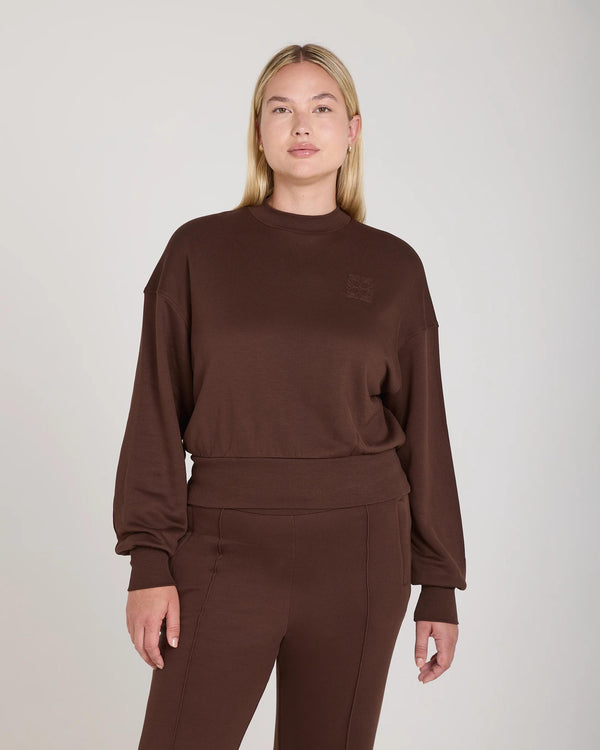 Model wearing chocolate brown lyocell fleece sweatshirt from Emello with relaxed fit and embossed logo.