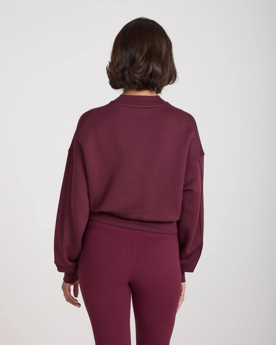 Back view of a fig-colored sweatshirt with debossed details, relaxed fit, and drop shoulder design.