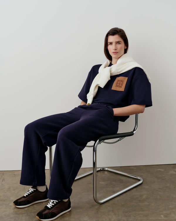 Model seated wearing Emello's Relaxed Straight Leg Trousers in Navy, showcasing refined casual elegance.