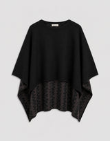Elegant black cape with reversible design showcasing plain-knit and geometric patterns.