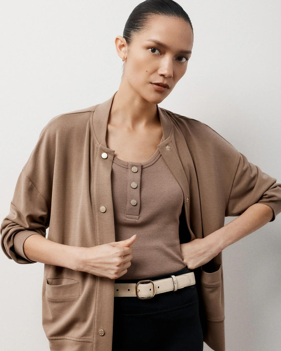 Model wearing Emello reversible leather belt in cream with a tan cardigan and top.