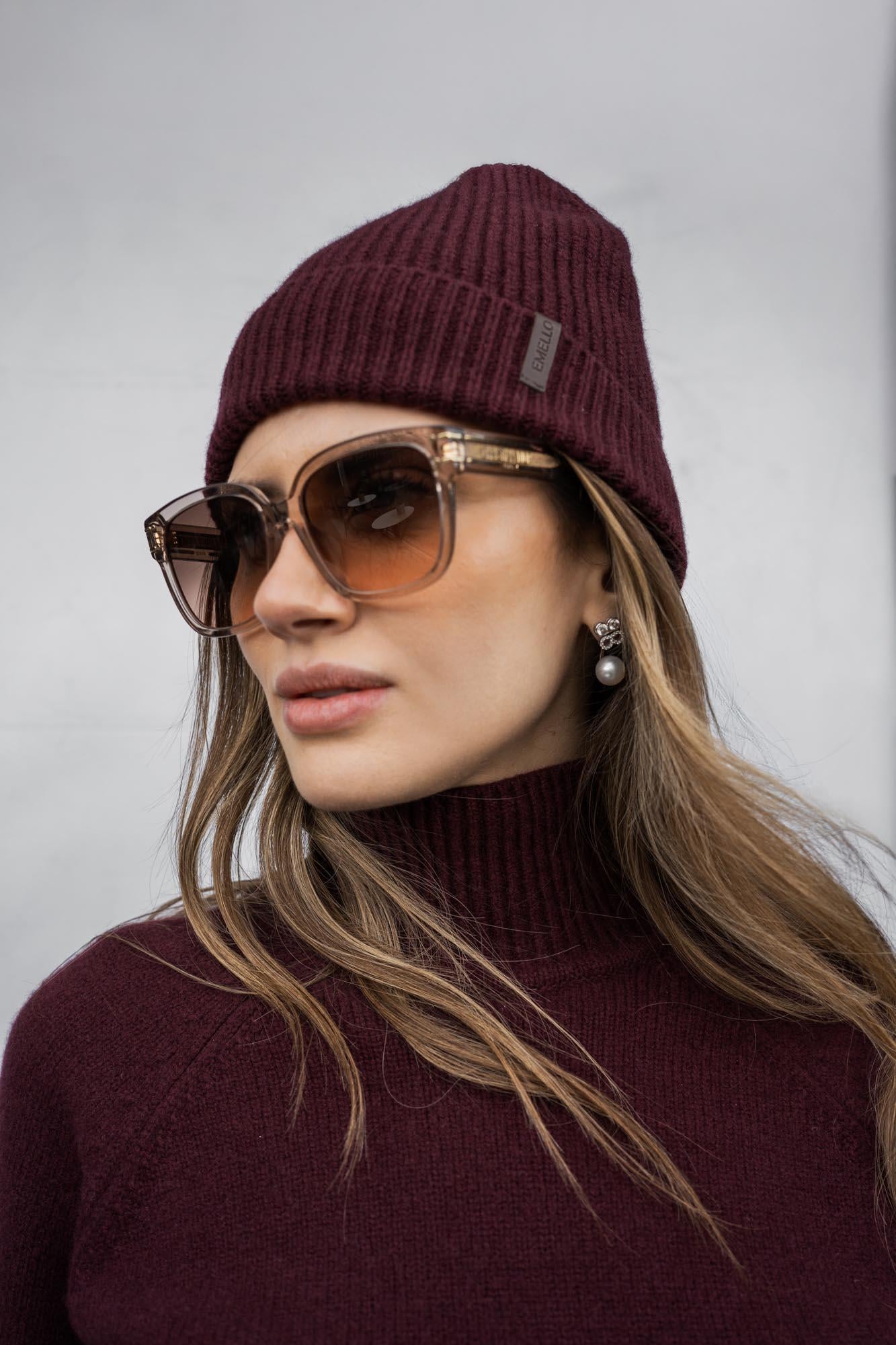 Close-up of woman wearing ribbed burgundy Emello cashmere beanie and turtleneck