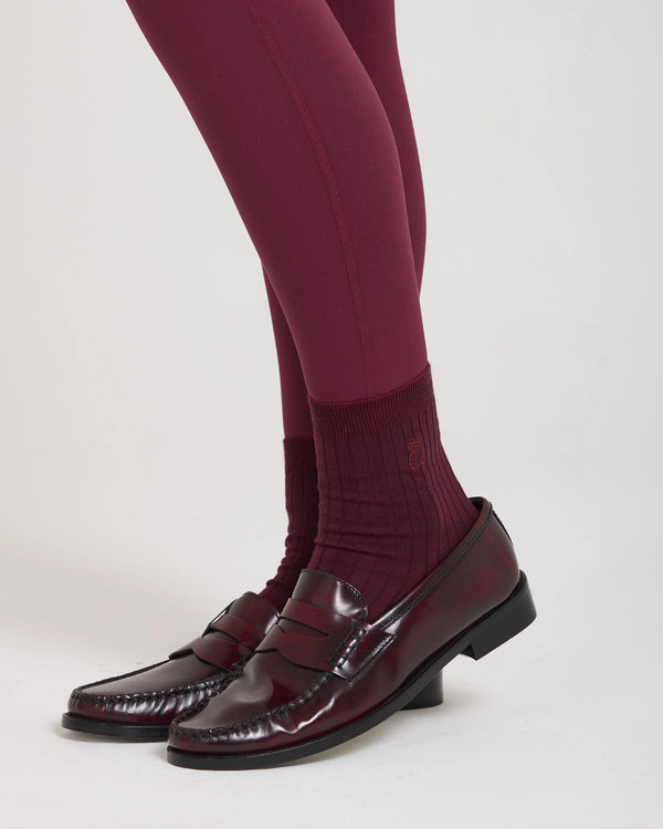 Burgundy half-crew socks with ribbed texture and subtle embroidery, styled with burgundy leggings and loafers.
