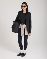 Elegant woman wearing cream ribbed cotton half-crew socks with embroidery, black blazer, black leggings, and loafers.
