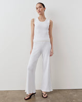 Model wearing Emello's tonal ribbed knit tank top in a bright cream, showcasing wide shoulders and soft scoop neckline.