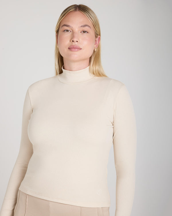 Forma Ribbed Lyocell-Cotton Blend Turtleneck Top in Beige, showcasing a sculpted fit with fine ribbing and a high collar.