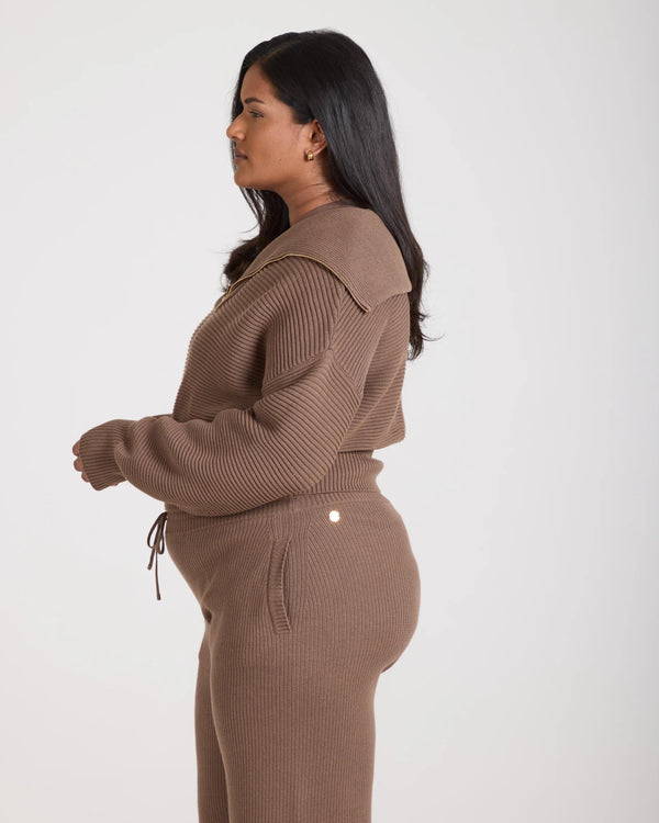 Side view of model wearing a taupe ribbed half-zip jumper crafted in Italy.