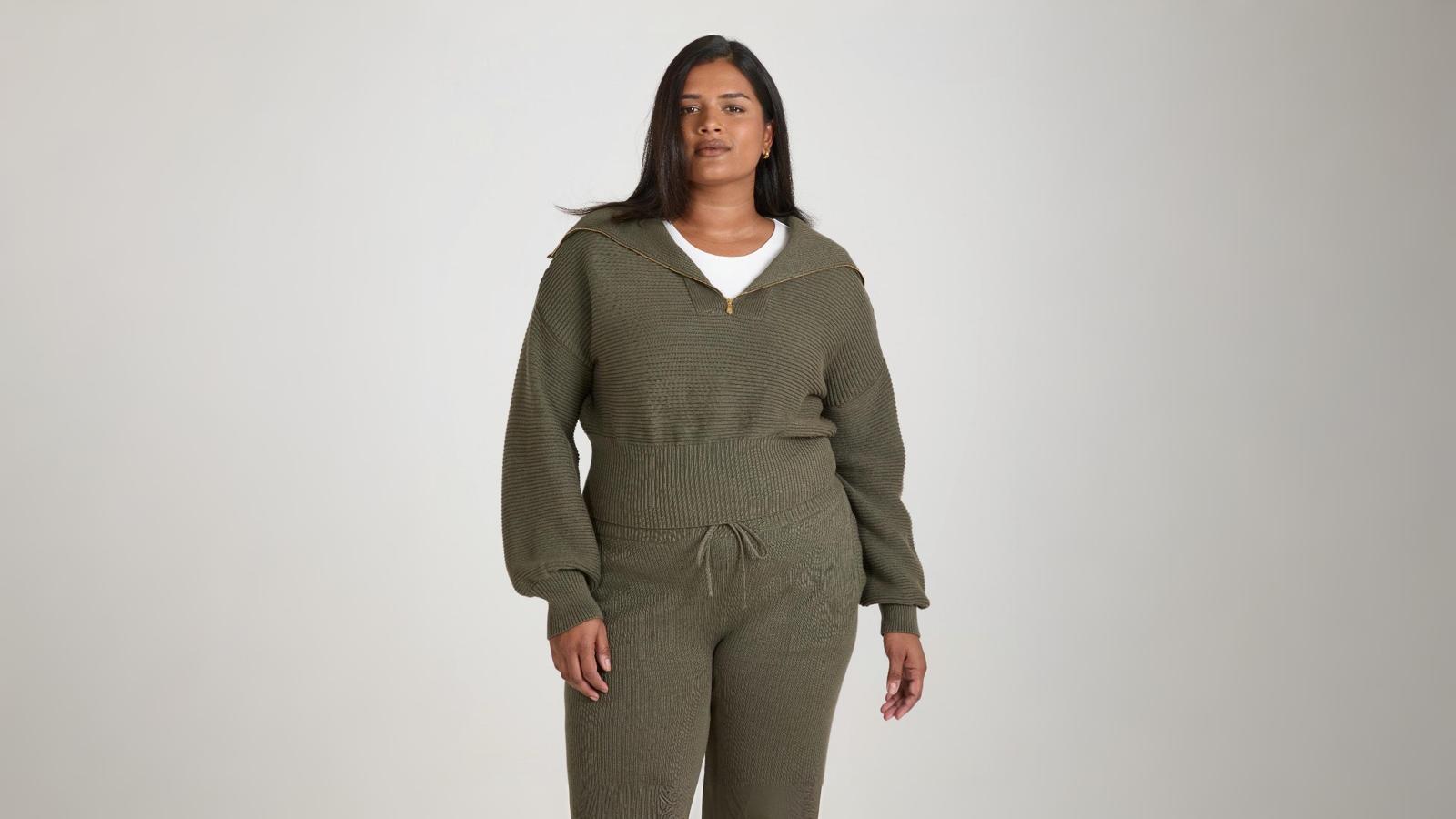 Woman wears ribbed olive knit pullover and pants set with soft drape and zip collar