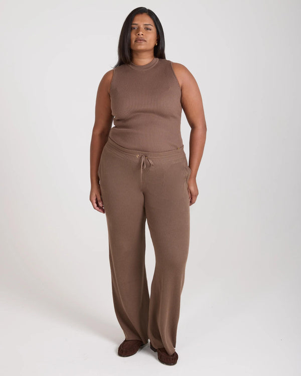 Model wearing taupe ribbed knit wide leg trousers with a relaxed fit, crafted in Italy.