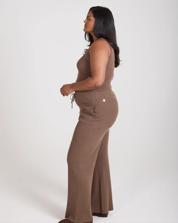 Side view of a model wearing taupe ribbed knit wide leg trousers by Emello