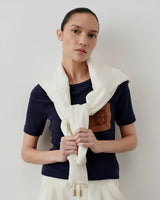 Emello Ribbed Pocket Tee in navy fitted on a model with a sweater draped over shoulders, showcasing elegant tactile elegance.