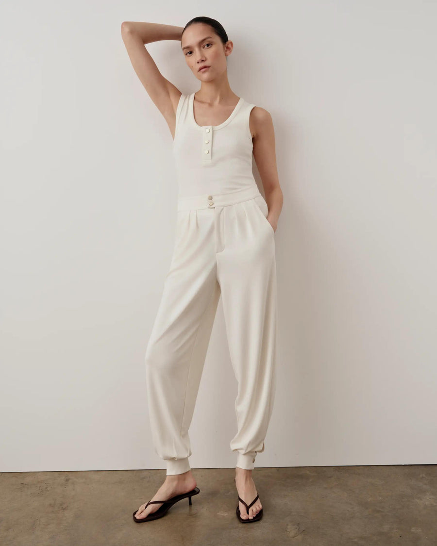 Model wearing Emello's ribbed popper tank top in cream with matching trousers and flip-flops.