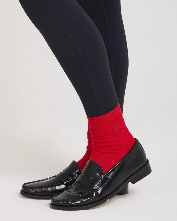 Ribbed red cotton half-crew socks with pale gold embroidery, styled with black shoes.