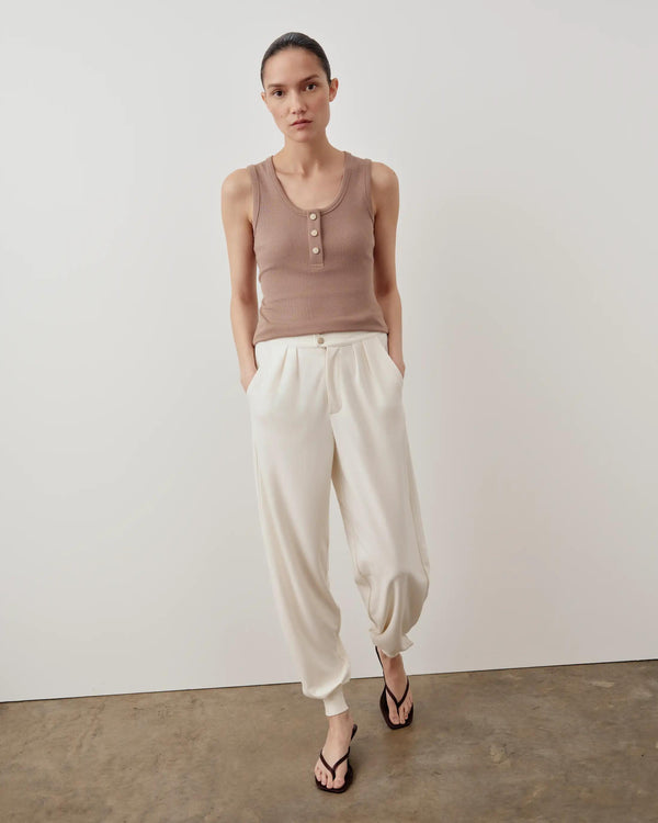 Emello Ribbed Popper Tank Top in taupe, showcasing a modern scoop neckline and brushed-metal poppers, styled casually with cream pants.