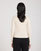 Back view of a women's beige ribbed turtleneck top, long-sleeved, worn with black trousers.