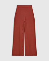Tonal Ribbed Knit Trousers in warm rust red, showcasing elongated silhouette and sculpted line.