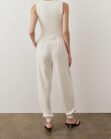 Back view of a woman wearing a cream ribbed popper tank top, showcasing its elegant, body-skimming fit.