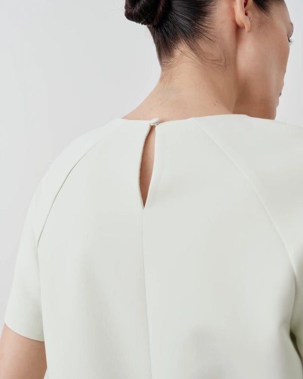 Back view of Emello's sculpted short-sleeve top in mist green with a keyhole button closure.