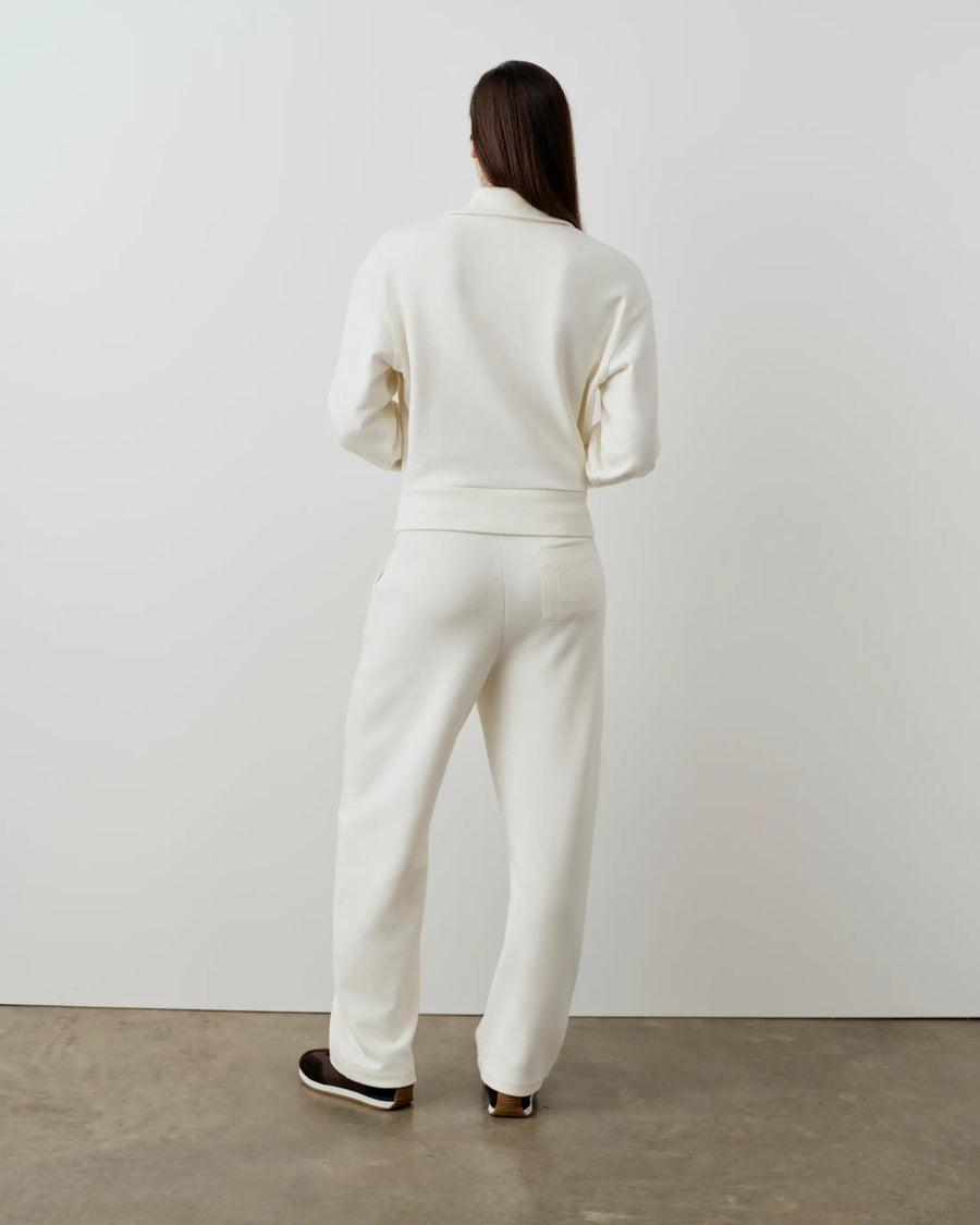 Rear view of a cream-colored half-zip funnel-neck sweatshirt with matching trousers, showcasing the relaxed fit and blouson form.