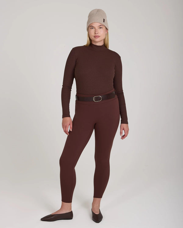 Model wearing Emello Forma Super Soft Sculpting Leggings in chocolate with belt loops, styled with a brown long-sleeve top and beige knit hat.
