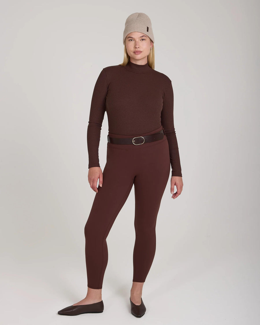 Model wearing Emello Forma Super Soft Sculpting Leggings in chocolate with belt loops, styled with a brown long-sleeve top and beige knit hat.