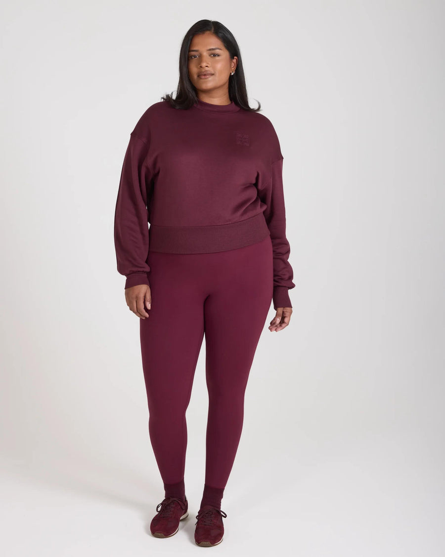 Model wearing Emello's fig-colored leggings with belt loops, showcasing a form-fitting silhouette.
