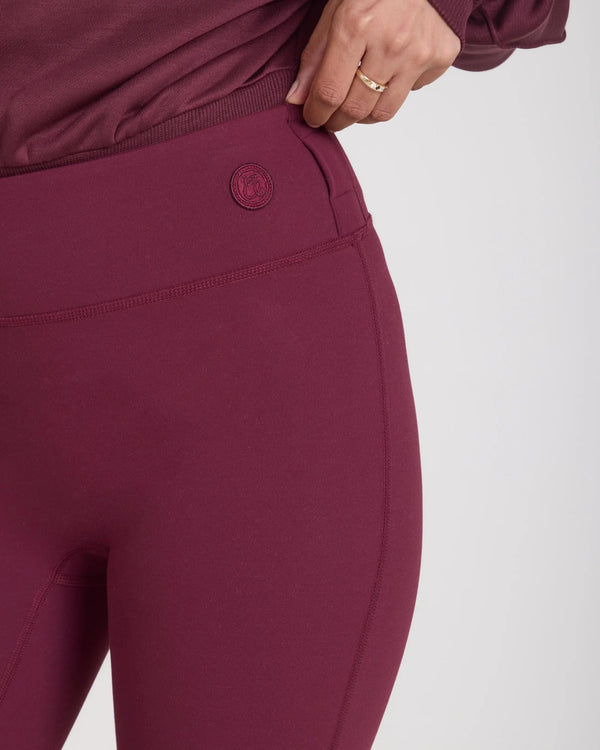 Close-up of a woman wearing fig-colored leggings with belt loops, showcasing a sculpting silhouette.