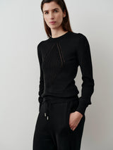 Silk Blend Pointelle Sweater in black, with intricate geometric panels and blouson sleeve shaping, worn by a model against a softly lit neutral background.