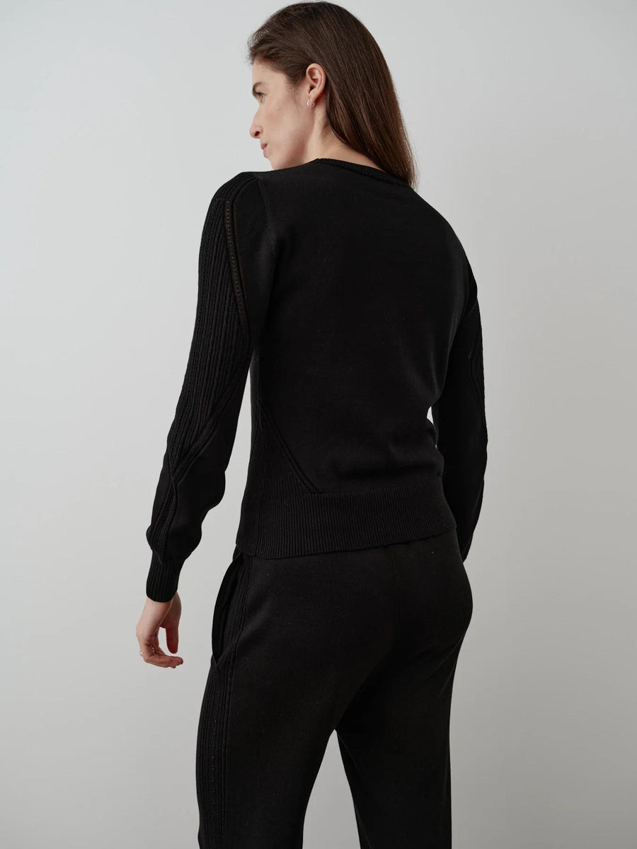 Back view of a black silk-blend pointelle sweater with intricate geometric detailing and blouson sleeves.